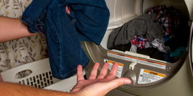 Man grabbing wet clothes out of a dryer