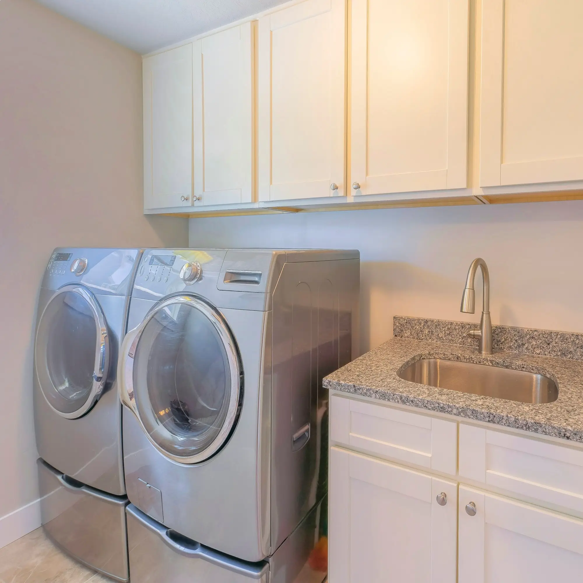 front load washing machine and dryer near cabinets and sink