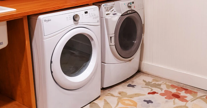 A front-loading washing machine and dryer next to each other under a countertop.